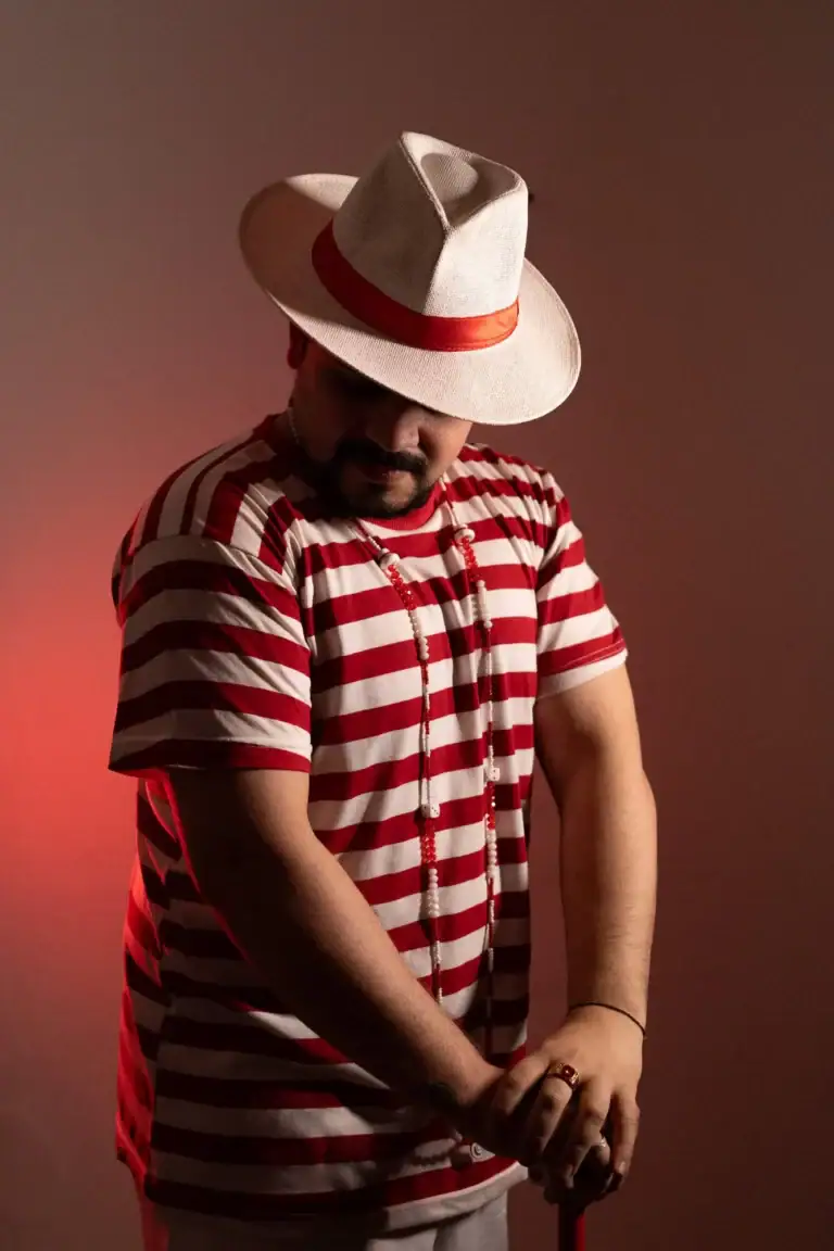 Fotógrafo Guilherme Marques com chapéu e camisa listrada vermelha e branca.