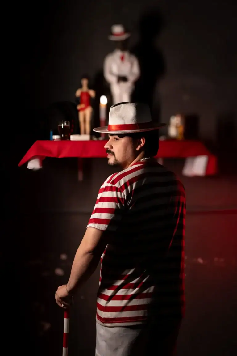 Fotógrafo Guilherme Marques com chapéu em estúdio com objetos de cena ao fundo.