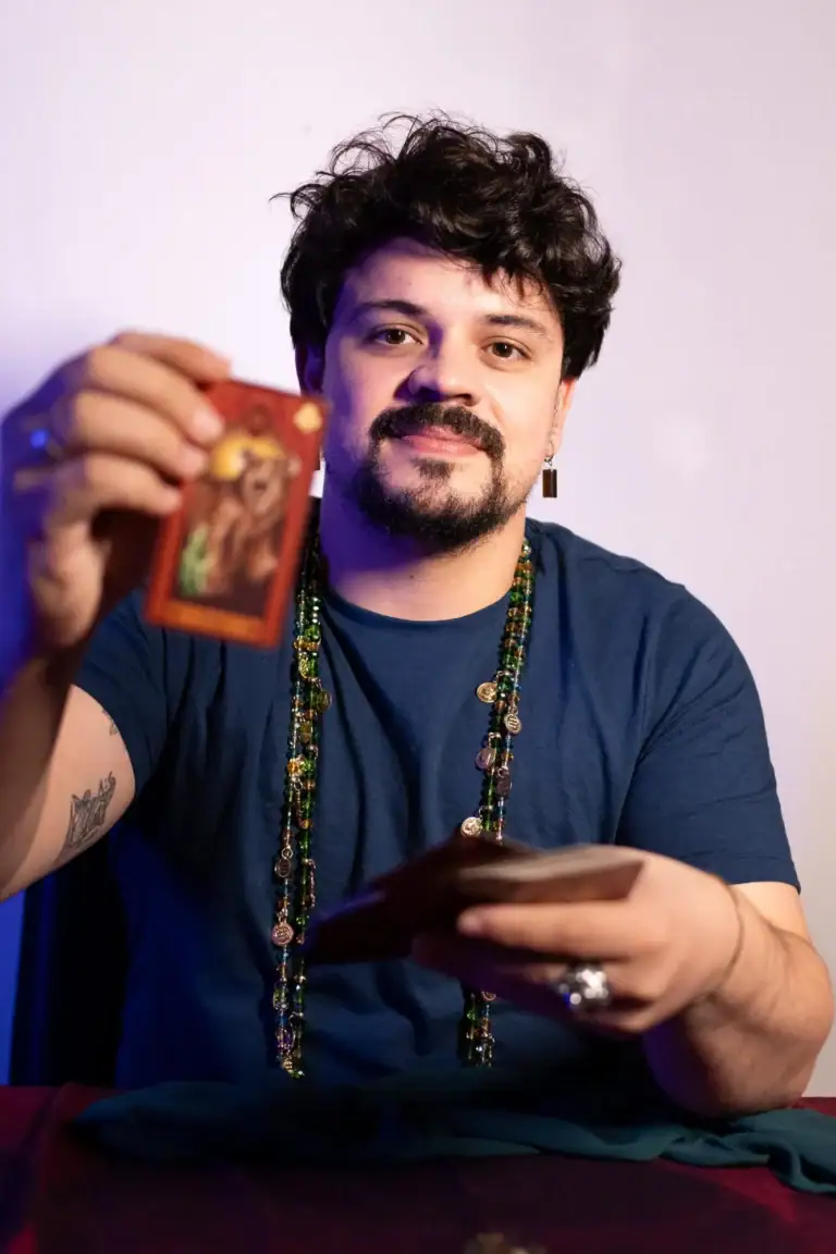 Fotógrafo segurando uma carta de tarot com fundo neutro.